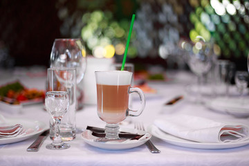 Delicious latte coffee in glass jar with straw on restaurant background