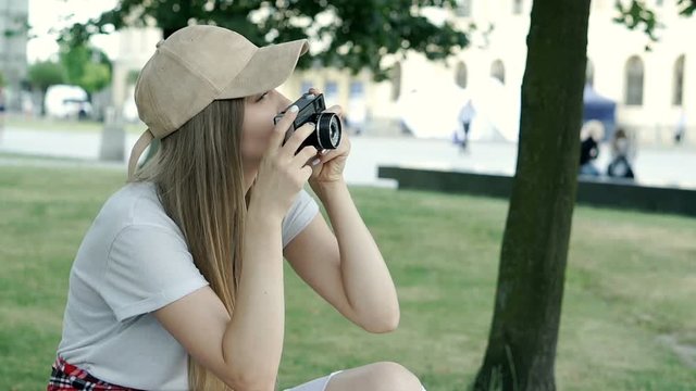 Stylish girl in ripped jeans doing photos on old vintage camera, steadycam shot
