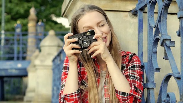 Pretty girl in checked shirt doing photos on old camera and looks happy, steadycam shot
