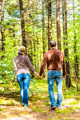 Back of young couple holding hands walking through fairy tale forest with mossy ground in West Virginia