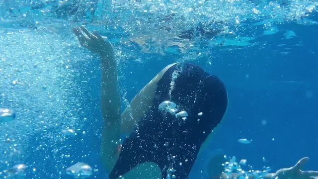 Girl swimming underwater and doing a forwards roll
