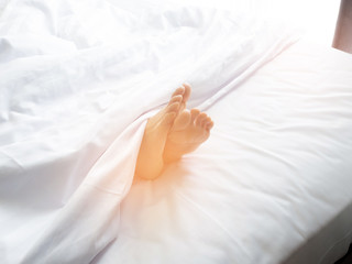 Feet of sleeping woman in white bed room.feet of a young woman lying in bed close up.