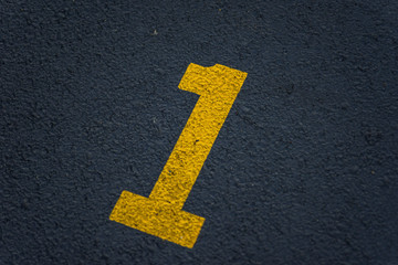 stenciled number 1 one in yellow paint on blacktop in parking lot - for use as background