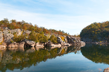 Obraz premium A scenic river bend in Great Falls park, Virginia, USA. Mountainous banks of Potomac River with trees in autumn foliage.