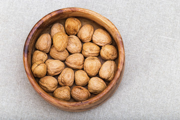 Walnuts lie inside a wooden bowl. Top view. Copyspace for text.