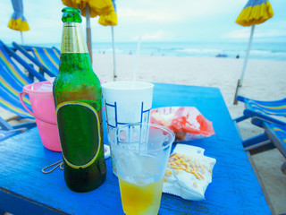 green bottle and dessert on the table from beach at eastern of thailand with blue sky and beach background(soft focus)