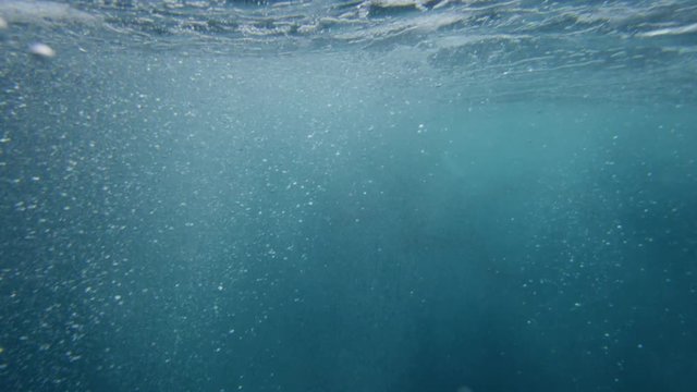 A medium shot of underwater while bubbles floating showing a part of the scuba divers fin.