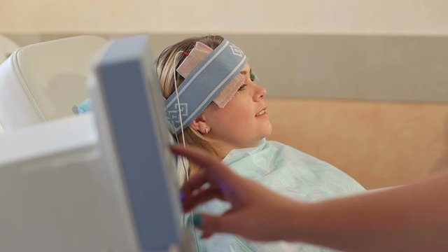 Close-up girl lying on the couch in the hospital for mesodiencephalic modulation of the brain. Electro-stimulation of the brain. Repair therapy. Physiotherapeutic procedures.