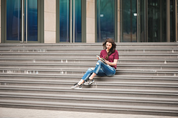 Beautiful woman reading a book on the steps of the building.