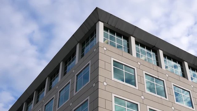 Motion of cloudy sky with illuminated reflected glass facade on modern office building