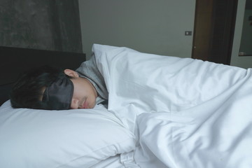 Young man with sleeping mask sleep on the  bed