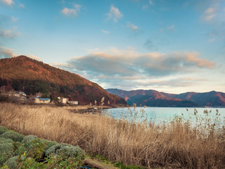 landscape view from kawaguchi lake with cloudy sky and sunshine on autumn forest background (soft focus) from japan