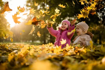 Foto op Canvas Kids having fun in park, throwing up leaves. © Martinan