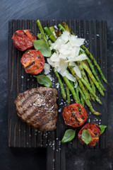 Top view of barbecued beef medallion steak with asparagus and tomatoes, vertical shot