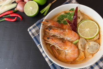Tom Yum Kung spicy and sour soup on dark wooden table top view.The popular food in Thailand.Thai food flat lay.