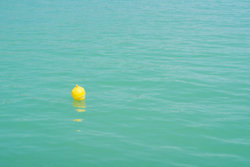 One bright yellow marker buoy floating in blue turquoise lake water, Balaton, Hungary. Abstract composition of water safety.