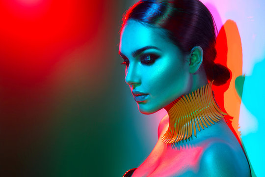Fashion model woman in colorful bright lights posing. Portrait of beautiful sexy girl with trendy makeup