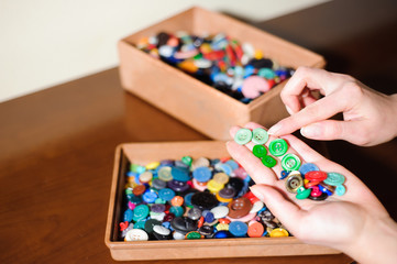 colorful sewing buttons in the hands, selection of the right buttons
