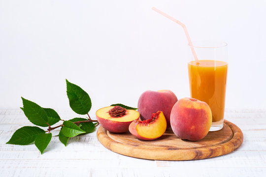 Peaches and peach juice on white wood background