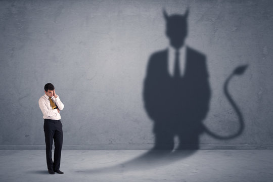 Business man looking at his own devil demon shadow concept