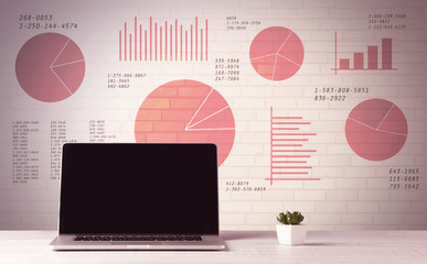 Laptop on office desk with sales pie charts