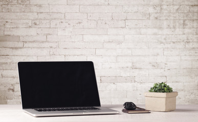 Business laptop with white brick wall