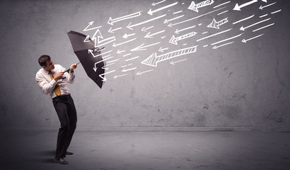 Business man standing with umbrella and drawn arrows hitting him