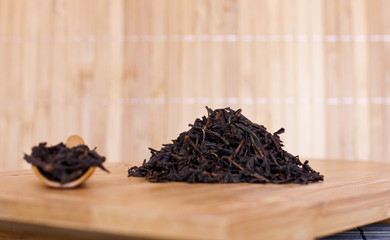 Black friable tea on a wooden tray