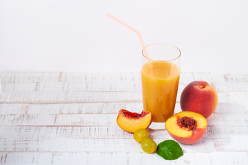 Peaches and peach juice on white wood background