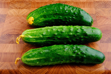 fresh green cucumbers on wooden cutting board close-up
