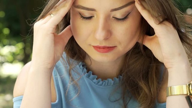 Attractive woman stops reading book because of the painful headache, steadycam shot
