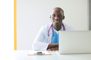Portrait of young male doctor wearing headset while using computer at desk in clinic. Doctor.
