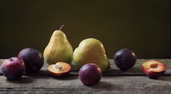 pears and plums on wooden table