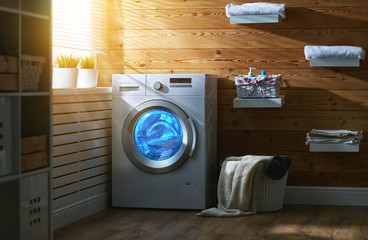 Interior of real laundry room with  washing machine at window at home