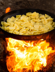 Potatoes fried in a frying pan in the open air