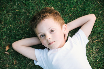 cute little kid relaxing lying on green grass