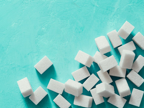 Top view of white sugar cubes on blue concrete background