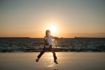 Fototapeta na wymiar adorable little boy jumping on the background of the setting sun and the sea