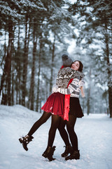 Close up fashion portrait of two sisters hugs and having fun, drinking tea winter time,wearing red santa hats and sweater,best friends couple 