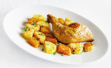 roasted with spices and garlic chicken leg garnished with potato and pumpkin