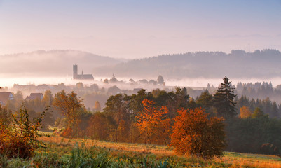 Tower of rural church in misty autumn morning.