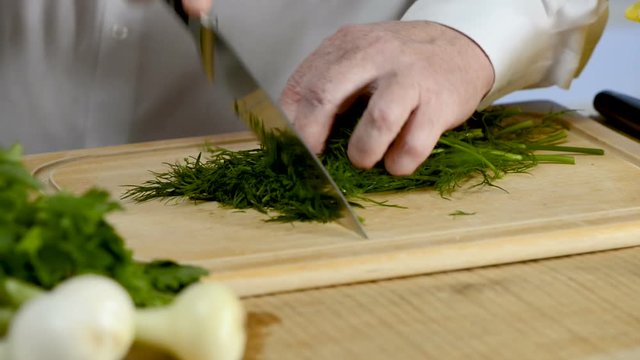 Hands of the cook knife big kitchen a fresh green fennel on a chopping board from a tree