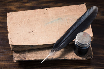 still life photography : inkwell and feather pen with old tex book on old wood