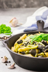 Creamy zucchini, mushroom, peas pasta in cast iron skillet. Selective focus, close up, copy space.