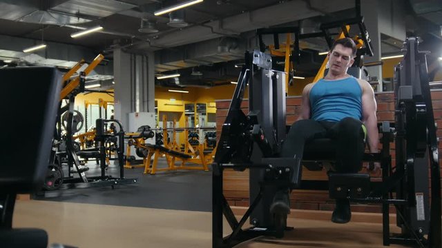 The gym - man doing training for legs - wide angle