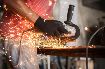 Electric wheel grinding on steel structure in factory
