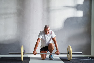 Senior man preparing to lift weights at the gym