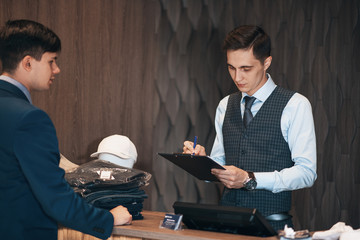 seller in the classic clothes shop with the buyer signs the contract on the tablet.