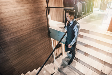 young man dressed in a luxurious suit descends the stairs