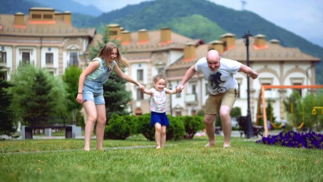 Happy family playing fun on green grass in summer.